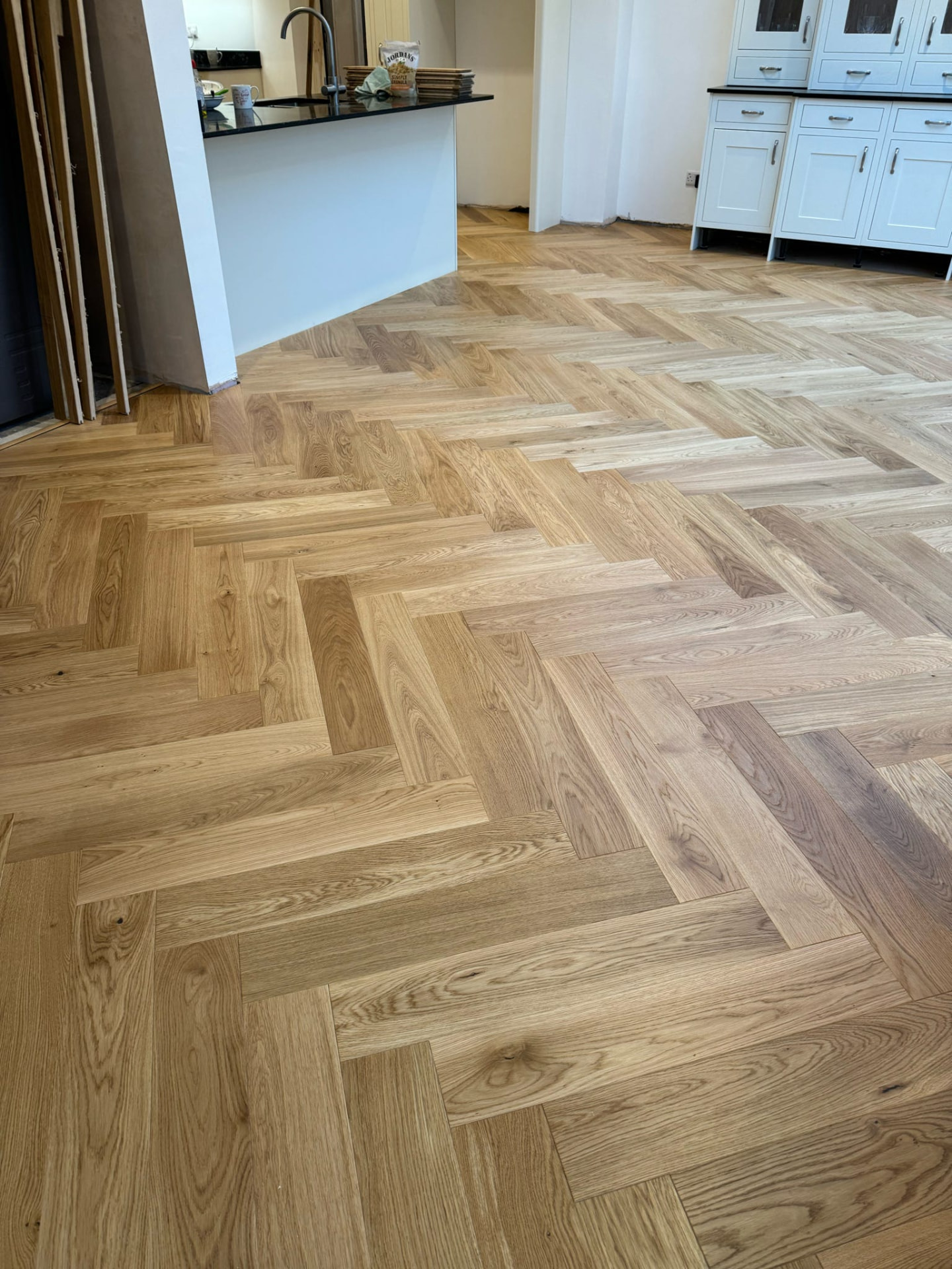 Herringbone oak floor fitted in a bright open-plan kitchen