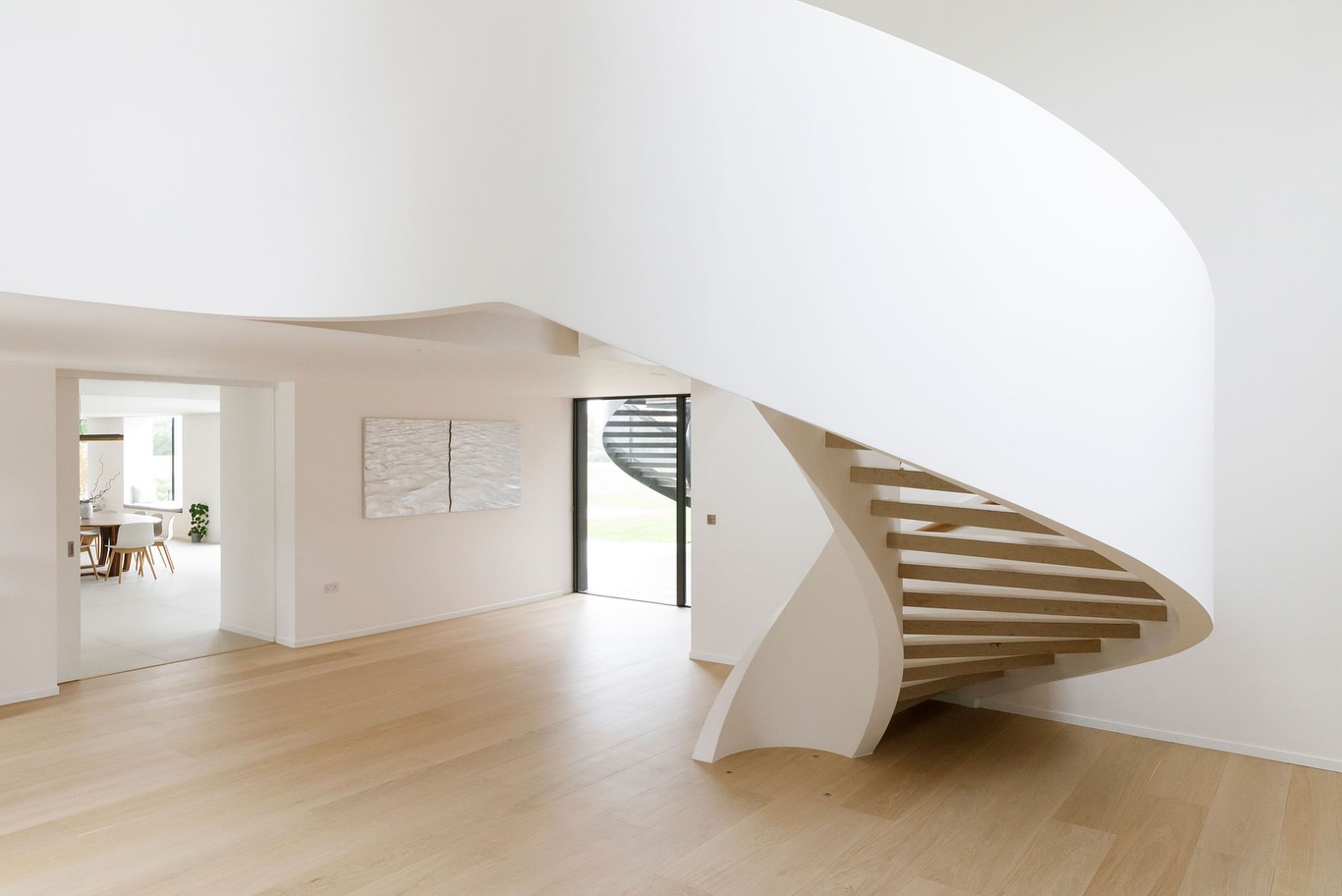 Light oak flooring beneath a sculptural spiral staircase